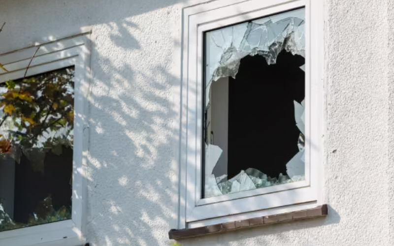 Emergency glazier securing a damaged window after glass breakage.