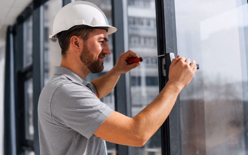 Emergency glazier boarding up a broken window to secure a property.